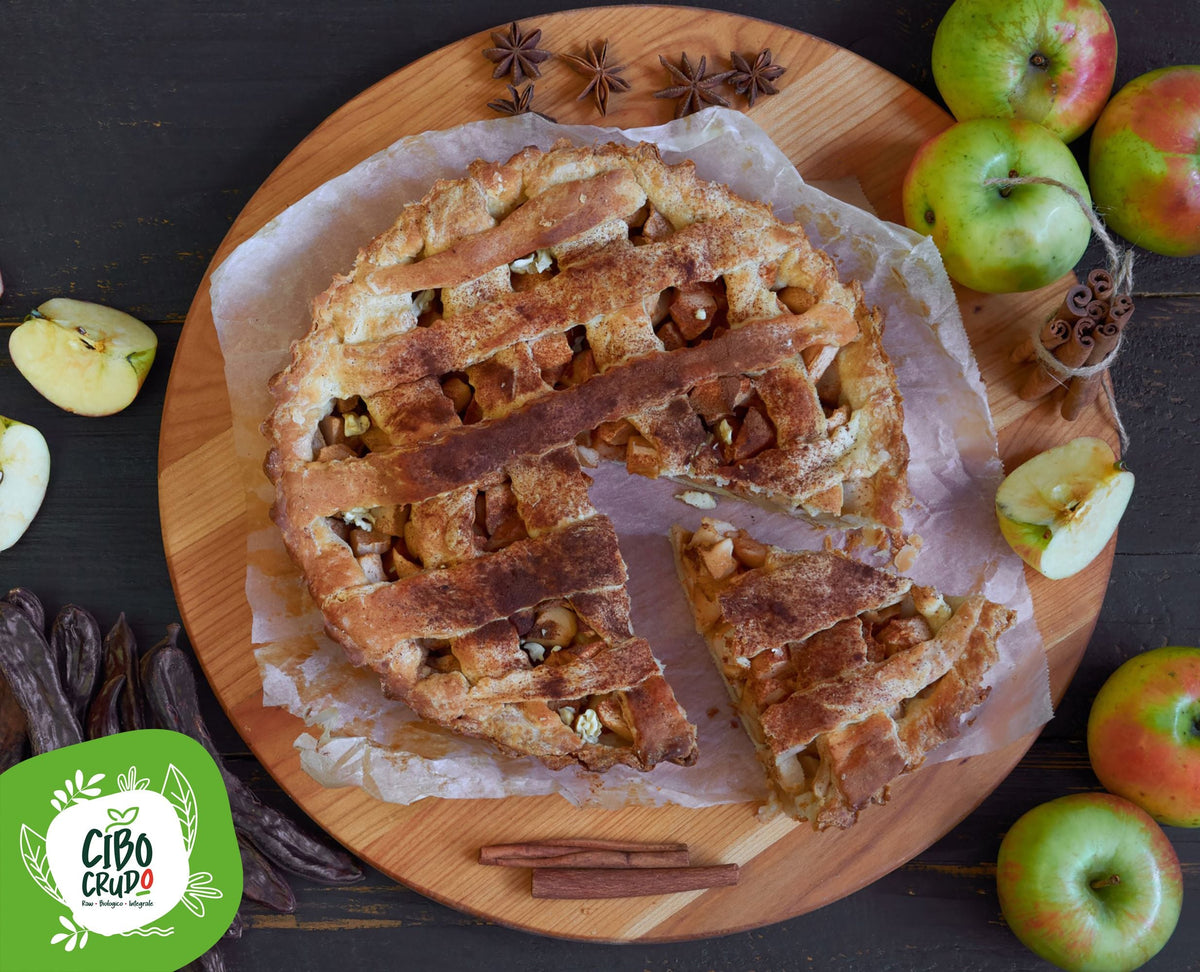 Crostata di mele con farina di carrube, decorata con cannella, mele fresche e baccelli di carruba