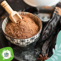 Ciotola di farina di carrube con cucchiaio di legno, baccelli secchi e anice stellato sullo sfondo